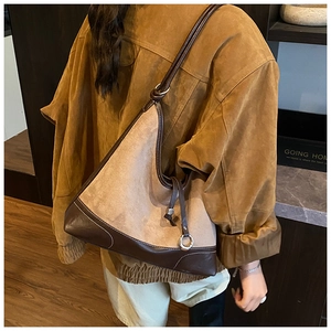 Detail of khaki suede tote bag with brown leather trim worn as an underarm shoulder bag
