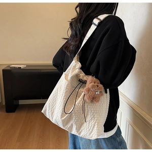 Detailed side view of a white bubble texture bucket bag with adjustable wide strap