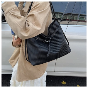 Detail of black pleated tote bag with vertical textures and silver hardware accents