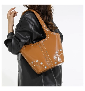 Dettaglio borsa tote in pelle lucida marrone con borchie argentate e occhielli