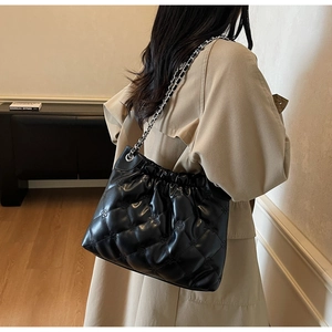 Détail du sac seau noir matelassé avec bandoulière chaîne argentée et motif floral