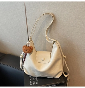 Detail of off-white hobo bag with embossed logo and a cute brown plush bear charm