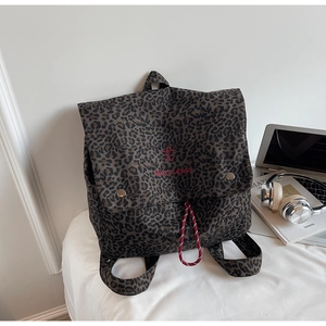 Detail of leopard print backpack with red embroidery and woven drawstring closure