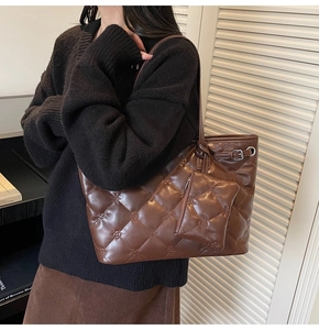 Détail d'un sac cabas marron matelassé avec gaufrage floral et petite pochette