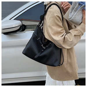 Detail of black pleated tote bag with decorative strap and silver metal buckle