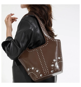 Dettaglio della borsa tote in pelle verniciata marrone con borchie e occhielli metallici