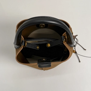 Detail of suede bucket bag interior with golden magnetic closure and zipper pocket