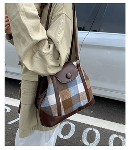 Detail of vintage plaid shoulder bag with brown leather trim and metal clasp closure