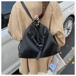 Detail of a black pleated backpack featuring a textured finish and metal buckle strap