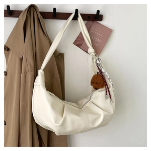 Detail of white pleated crescent bag with cute dog pendant and woven rope accessory