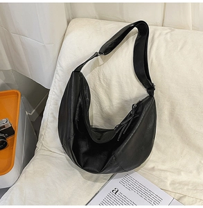 Vue détaillée du sac hobo en cuir noir en forme de croissant sur fond blanc doux