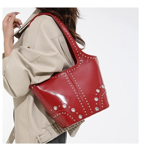Vista laterale della borsa tote in pelle verniciata rossa con borchie argentate indossata