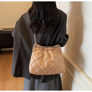 Détail du sac seau matelassé beige avec bandoulière chaîne et cordon de serrage