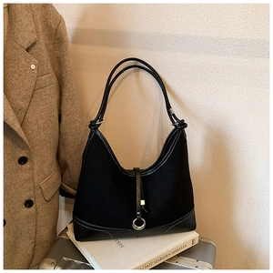 Detail of black Hobo bag with white stitching and silver ring buckle on white books