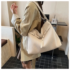Detail view of cream pleated tote bag featuring silver buckle and elegant texture