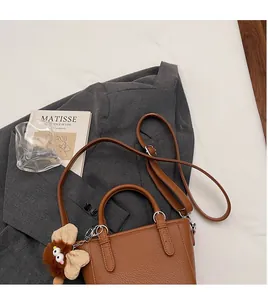 Brown lychee-grain leather tote with adjustable shoulder strap and owl charm