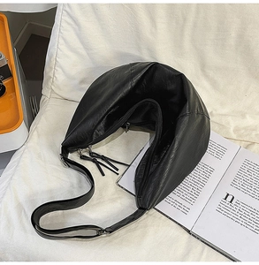 Détail d'un sac bandoulière croissant noir avec texture cuir et fermetures éclair