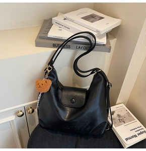 Close-up of black leather hobo bag with teddy bear charm and BAGS FASHION embossed logo