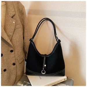 Detail of black tote bag with silver ring charm and mixed faux leather suede texture