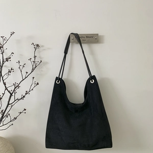 Detail view of large black suede tote bag hanging with metallic ring strap connectors