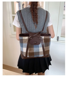 Detail view of the vintage plaid backpack with leather trim and metal ring shoulder straps