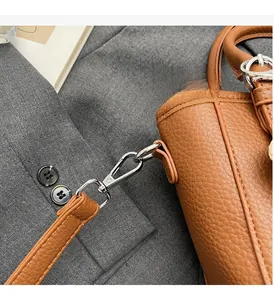 Close-up of silver metal buckle and brown pebble leather texture on women's handbag