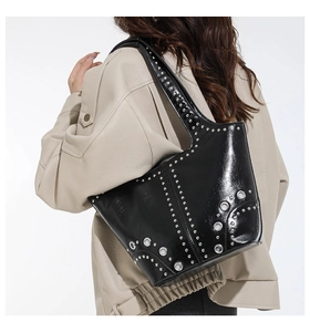 Dettaglio borsa tote in pelle verniciata nera con borchie argento e occhielli punk
