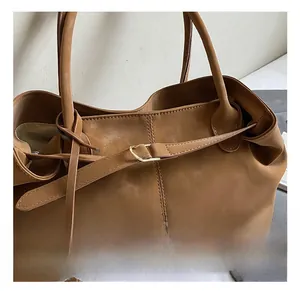 Close-up of golden metal buckle and decorative strap on brown suede tote bag