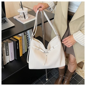 Close-up of white pleated shoulder bag featuring fine vertical textures and metal buckles