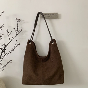 Detail view of deep brown suede tote bag featuring silver eyelets and slim shoulder strap