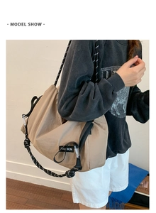 Detail of khaki nylon crossbody bag featuring stylish black and white rope shoulder straps