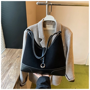 Detail of black suede tote bag with white stitching and silver metal ring decoration