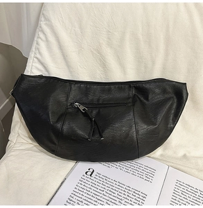 Détail d'un sac bandoulière noir en similicuir grainé avec fermeture éclair argentée