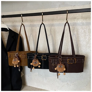 Close-up of retro suede bucket bags in caramel and black with cute bear charms