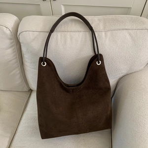 Detailed texture of dark brown suede hobo bag with silver metal eyelets and stitching