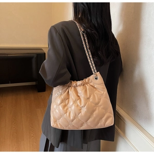 Sac à bandoulière matelassé beige avec chaîne argentée et fermeture à cordon sur modèle