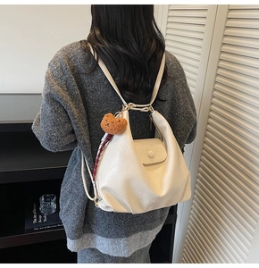 Detail of cream leather tote bag with embossed text and cute brown bear keychain accessory