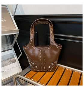 Dettaglio di una borsa a tracolla in pelle lucida marrone con borchie argento e occhielli metal