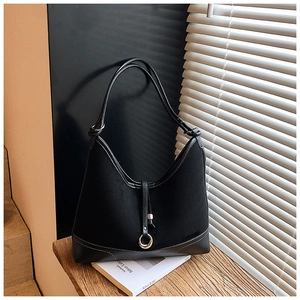 Detail of black leather tote bag featuring contrast white stitching and metal ring buckle