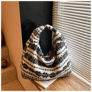Close-up of plush tote bag with black and white geometric patterns on a wooden window sill
