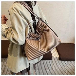 Close-up of brown pleated tote bag featuring vertical textures and leather strap detail