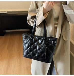 Détail d'un grand sac cabas noir matelassé avec pochette amovible et motifs losanges