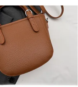 Detailed view of brown litchi grain leather texture and silver buckle on a handbag