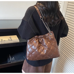 Détail du sac seau matelassé marron foncé avec bandoulière chaîne et logos gaufrés