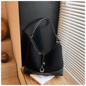Close-up of black canvas tote with leather trim and decorative metal ring detail