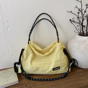 Close-up of yellow nylon tote bag with crinkle texture and braided rope handle