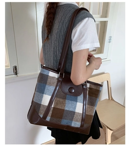 Detail of vintage plaid tote bag with brown leather handles and textured wool material