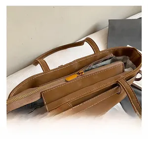 Detail of the golden metal zipper and geometric print lining on a brown suede tote bag