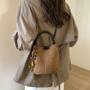Detail of vintage brown suede bucket bag with leather handle and clover tassel charm