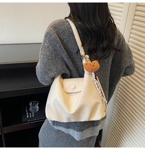 Detail of off-white PU leather shoulder bag with bear charm and checkered scarf accent